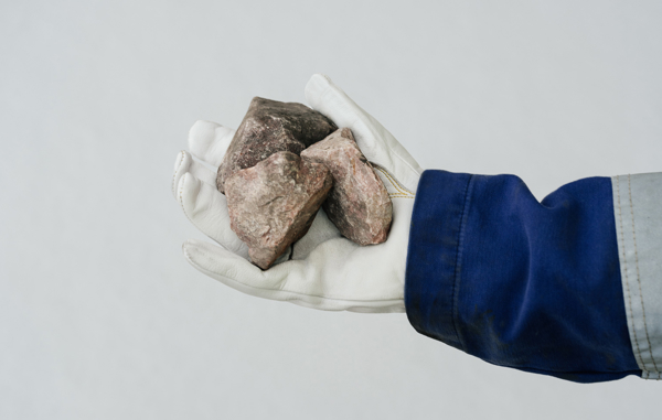 Hånd med hvit hanske holder en stein av kvarts